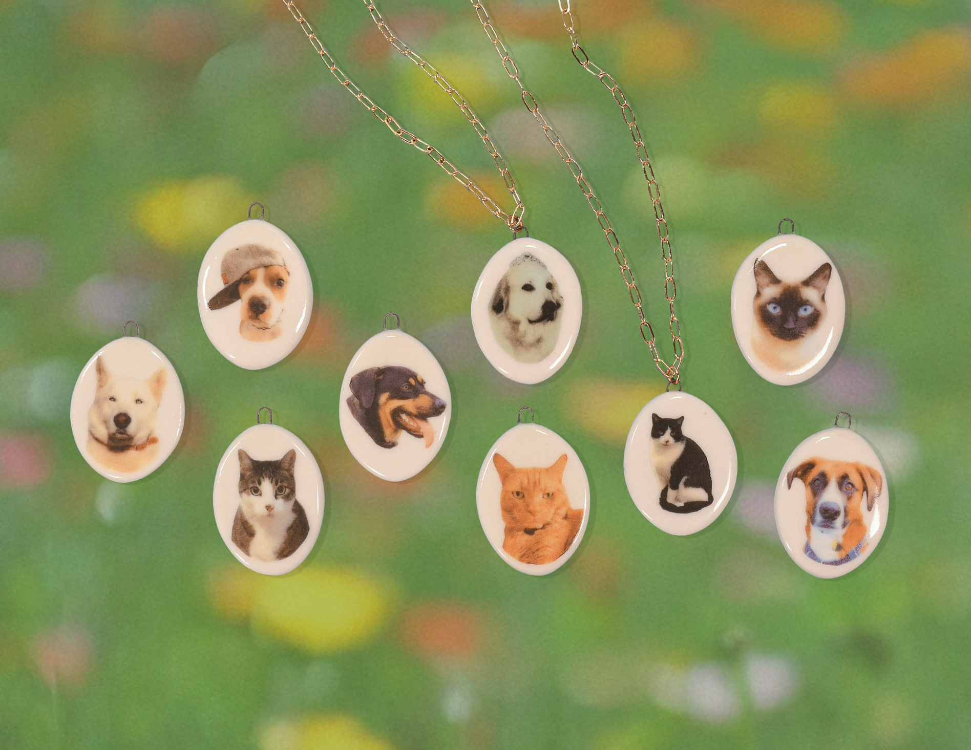 Necklaces with oval pendants featuring various dog and cat faces against a blurred green background.