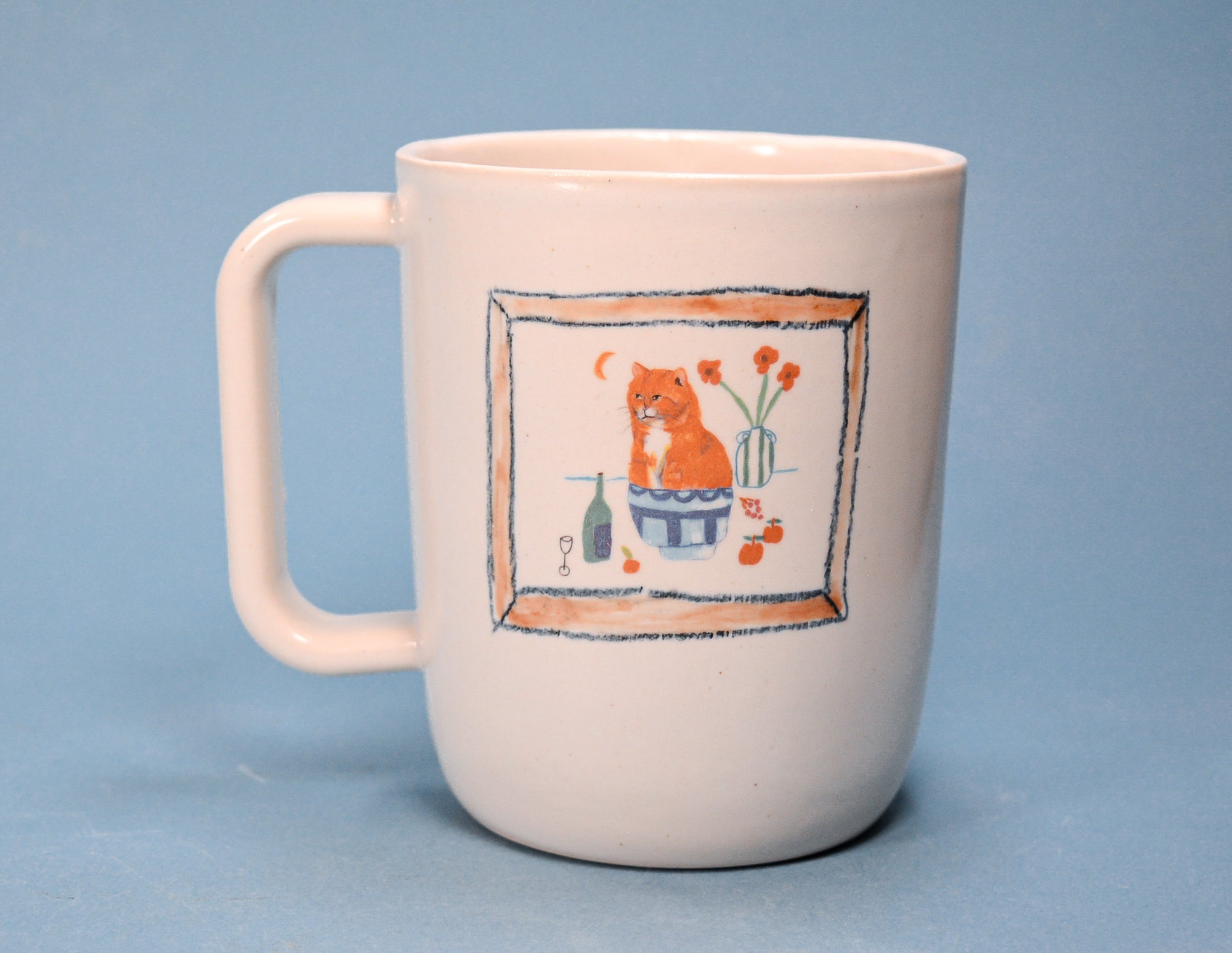 A white ceramic mug with a handle, featuring a hand-painted illustration of an orange cat sitting in a blue pot with flowers and a bottle, set against a solid blue background.