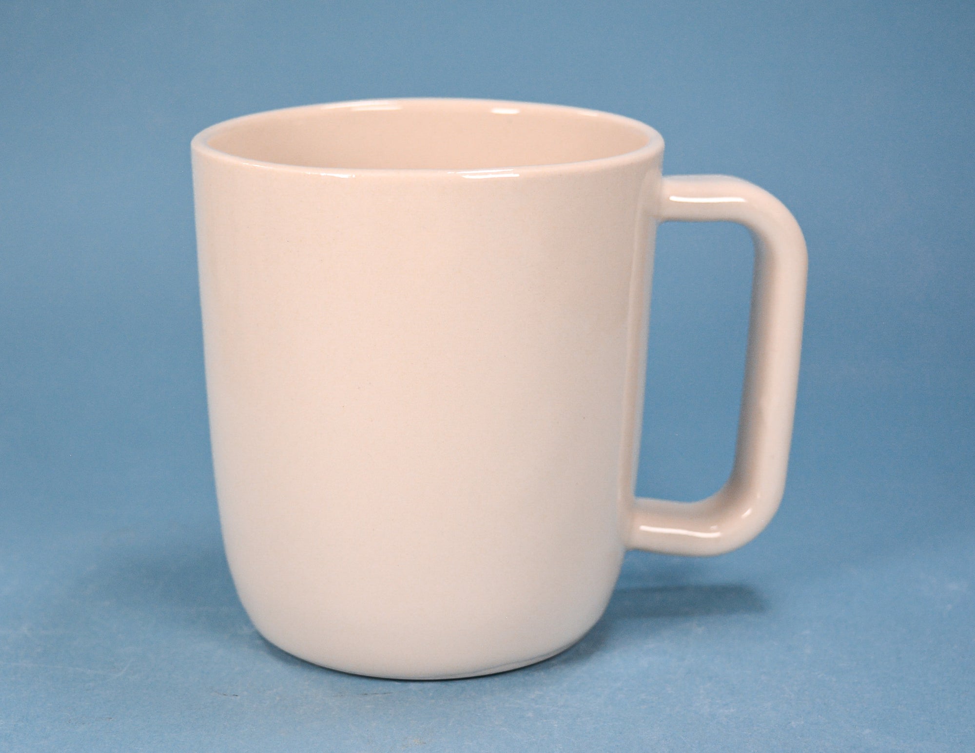 A plain ceramic mug with a rounded body and a rectangular handle, shown against a solid blue background.