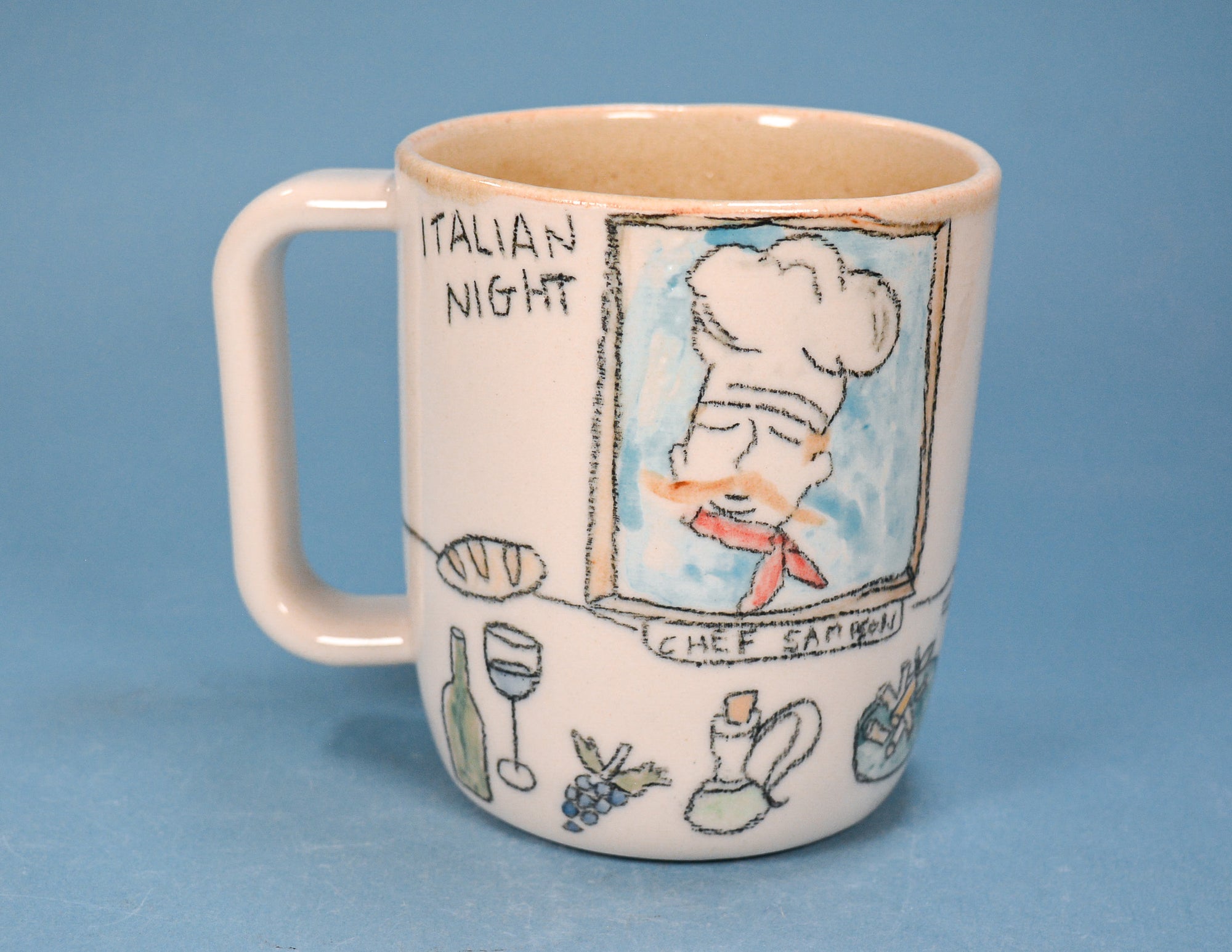A ceramic mug with a cream-colored exterior and a light beige interior, decorated with hand-drawn illustrations of an Italian restaurant scene. The artwork includes a chef, the text 'ITALIAN NIGHT' and 'CHEF EAT BEAN', and small drawings of wine, bread, and grapes, all set against a solid blue background.