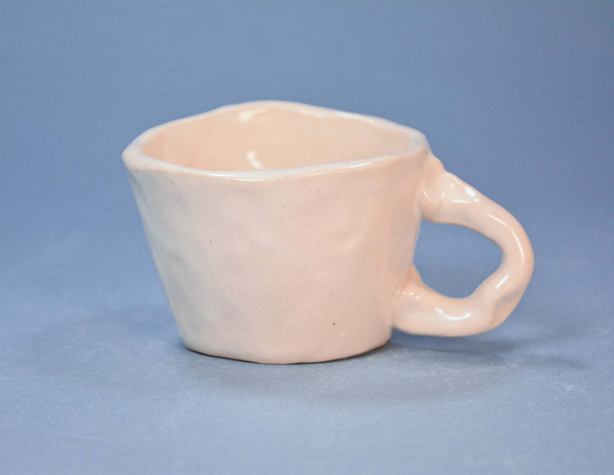 Back of ceramic cup with a handle on a blue background