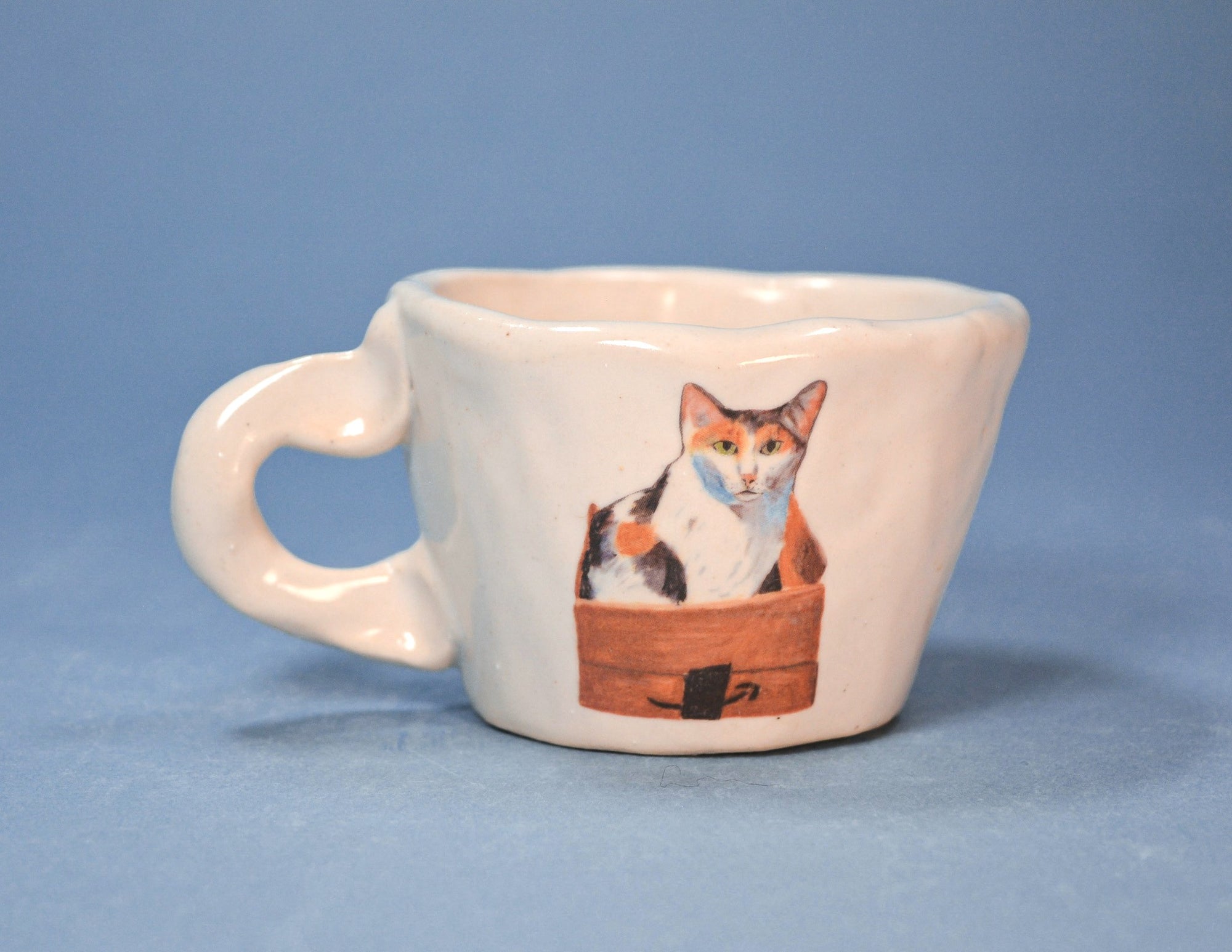 White mug with a cat illustration on a blue background