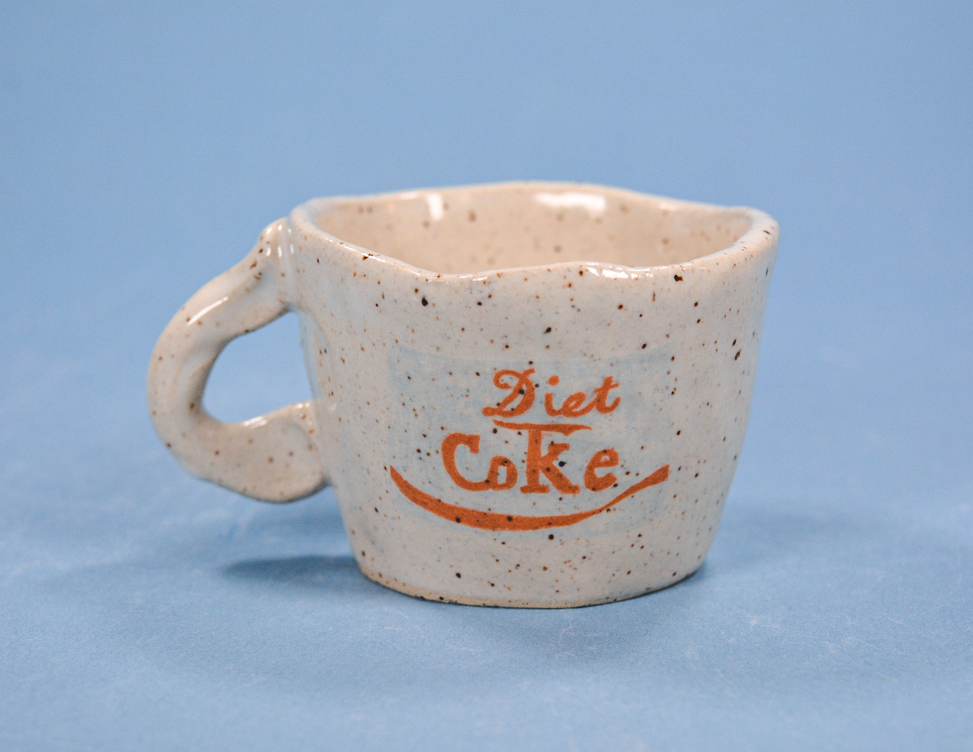 Speckled ceramic mug with 'Diet Coke' text on a blue background