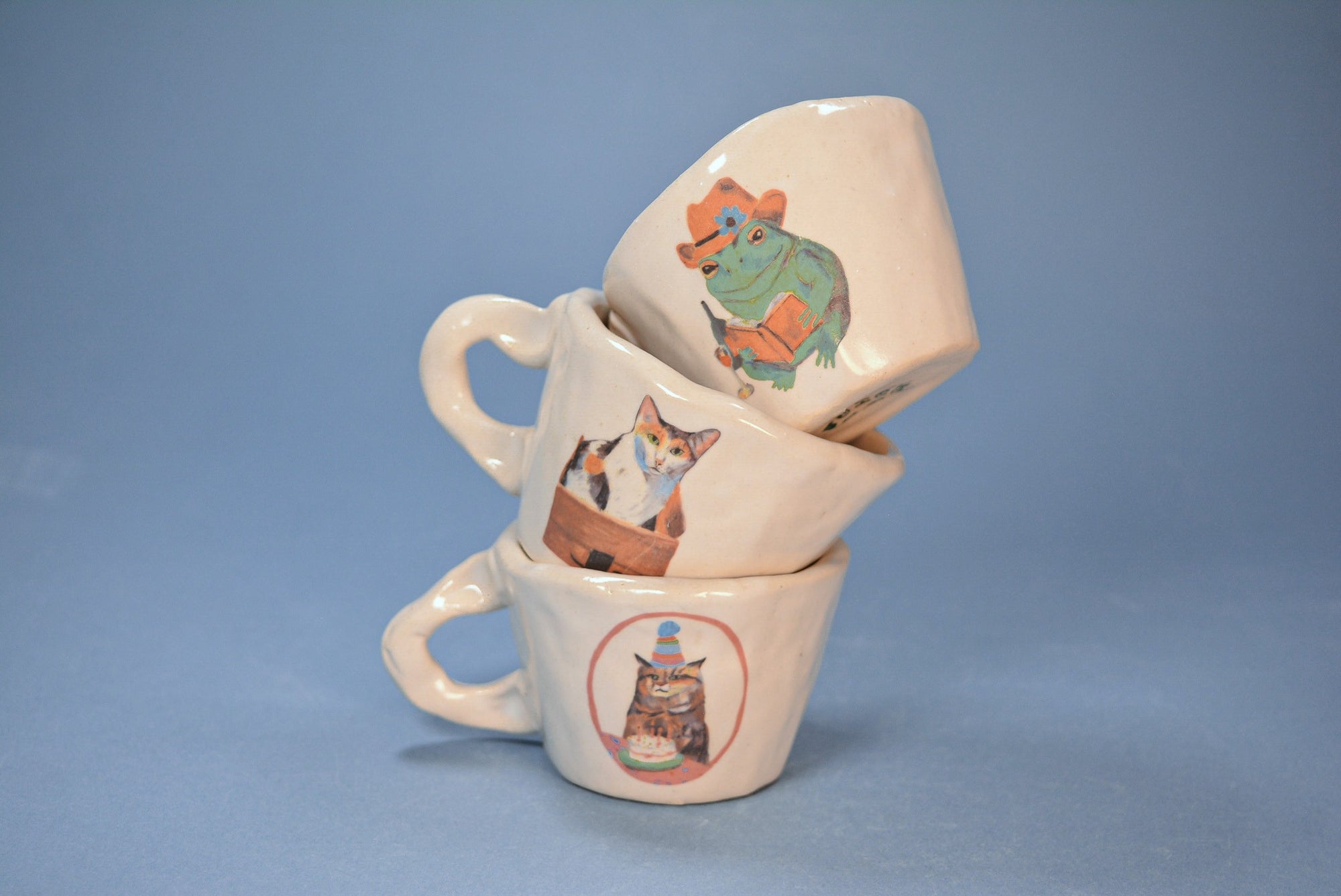 Stack of ceramic espresso mugs with animal illustrations on a blue background
