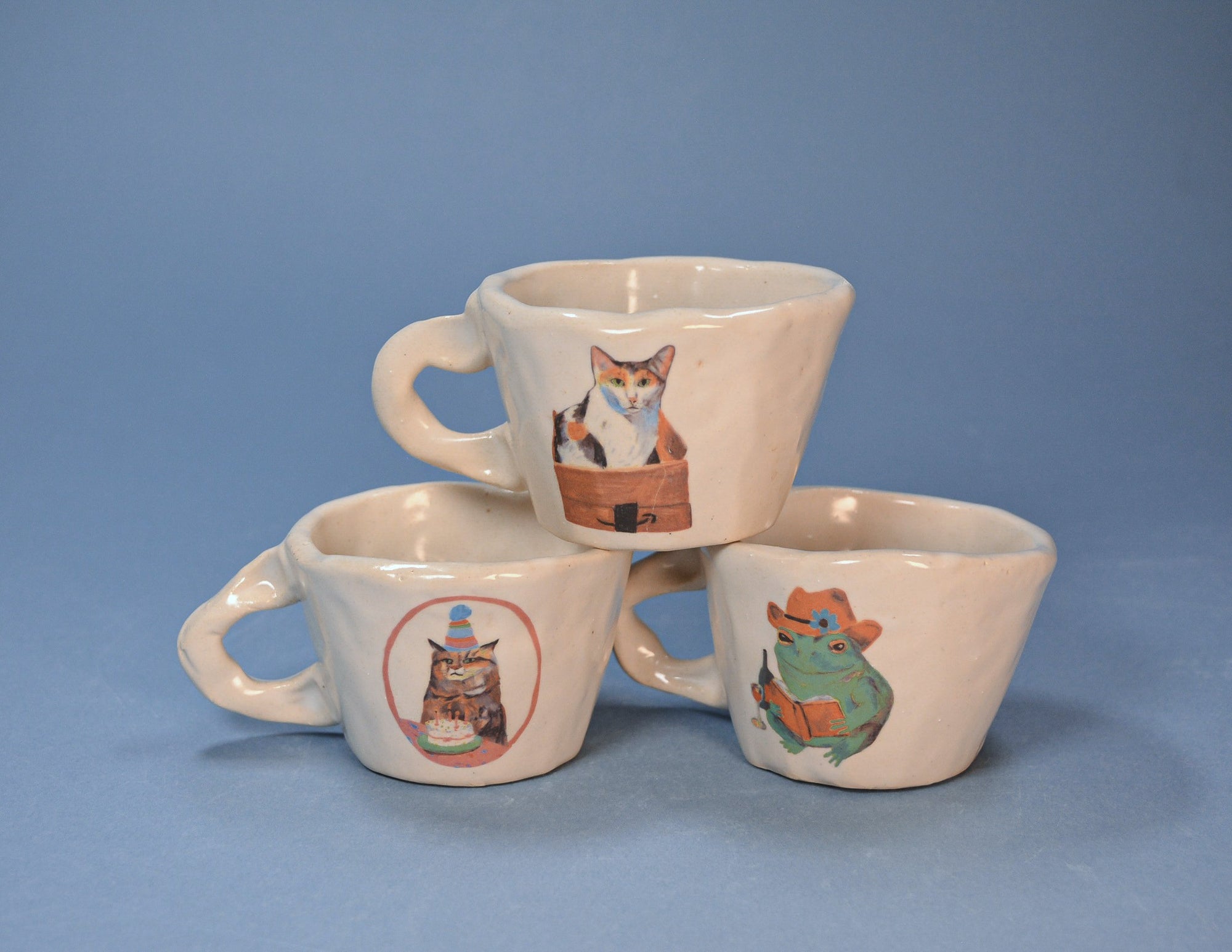 Three ceramic espresso mugs with animal illustrations on a blue background