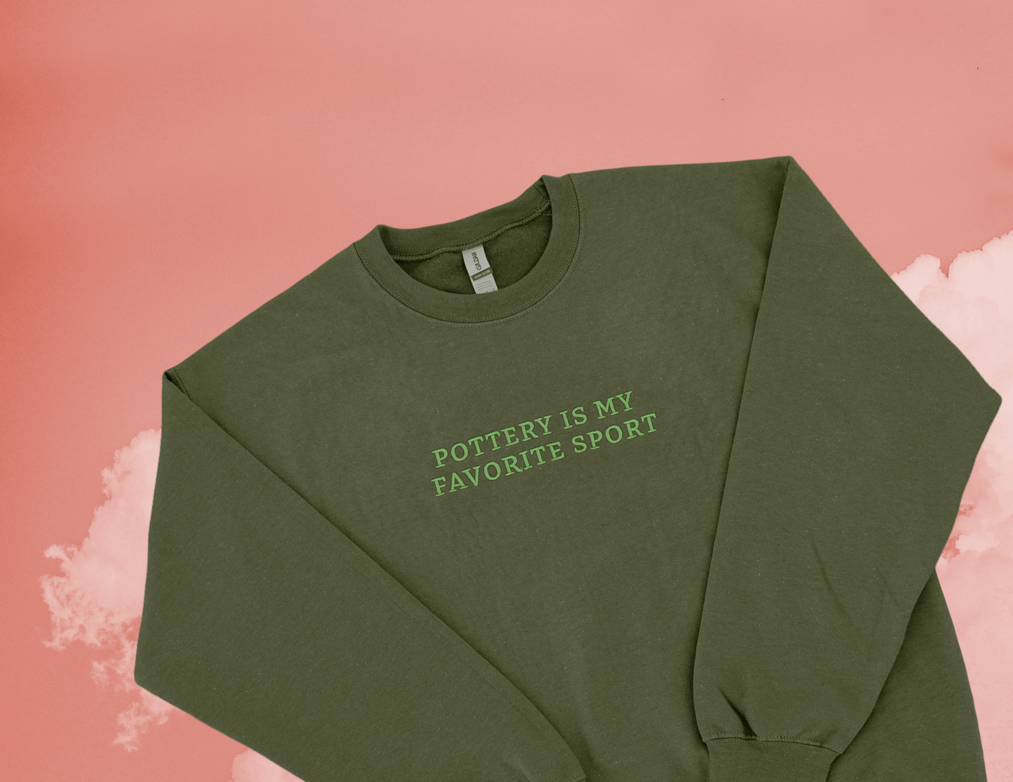 Close-up of embroidered Pottery Is My Favorite Sport text in white thread on spinach green sweatshirt